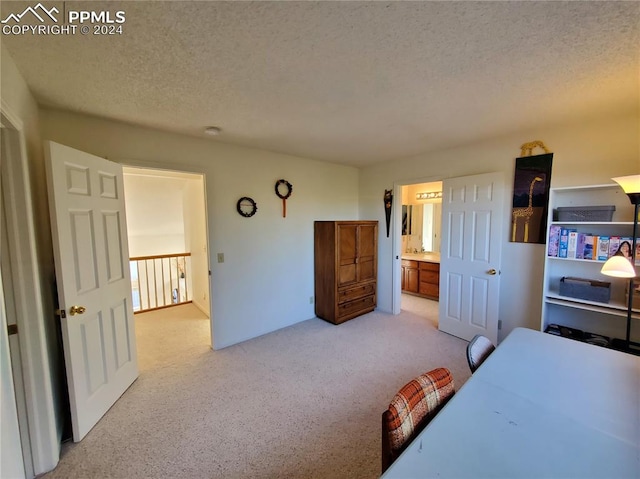 carpeted bedroom featuring ensuite bath and a textured ceiling