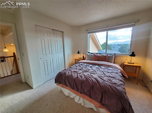 bedroom with a closet, light colored carpet, and a textured ceiling