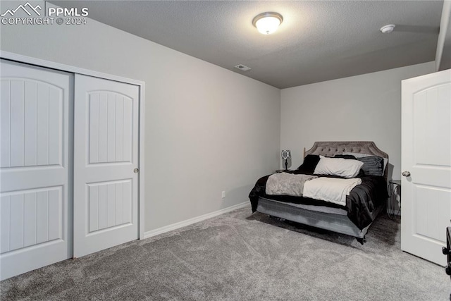 carpeted bedroom with a closet and a textured ceiling