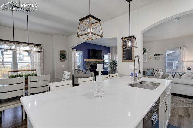 kitchen featuring sink, hanging light fixtures, an island with sink, and dark wood-type flooring