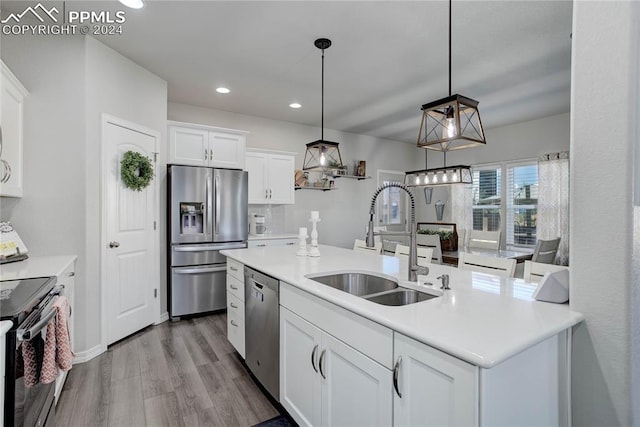 kitchen with decorative light fixtures, sink, white cabinetry, and stainless steel appliances