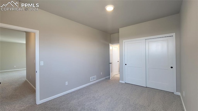 unfurnished bedroom featuring light carpet and a closet