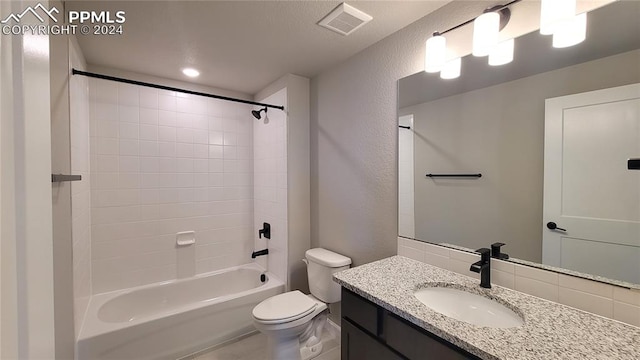 full bathroom with tiled shower / bath, vanity, and toilet