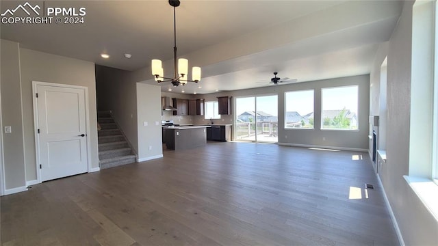 unfurnished living room with sink, ceiling fan with notable chandelier, and dark hardwood / wood-style flooring