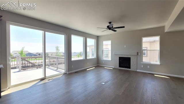 unfurnished living room with dark wood-type flooring, a tile fireplace, and ceiling fan