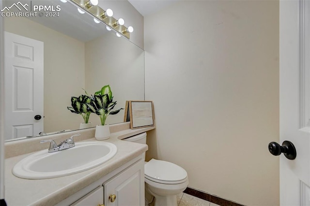 bathroom with toilet, vanity, and tile patterned flooring