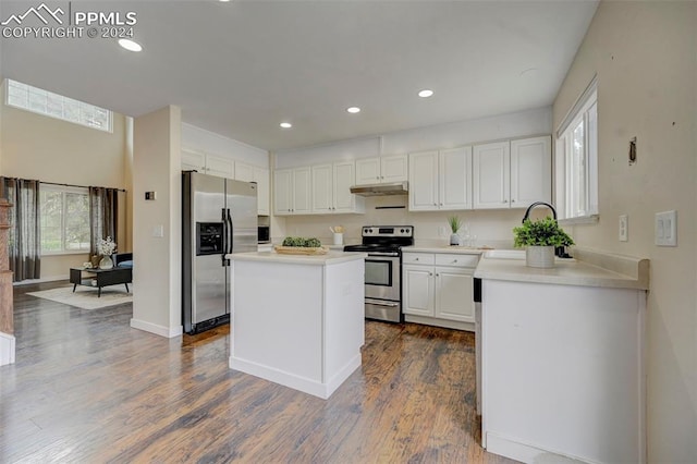 kitchen with white cabinets, stainless steel appliances, a kitchen island, and dark hardwood / wood-style floors