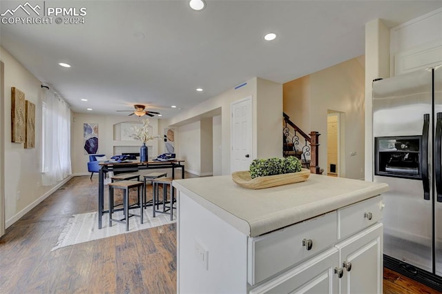 kitchen with a kitchen island, hardwood / wood-style flooring, stainless steel refrigerator with ice dispenser, white cabinetry, and ceiling fan