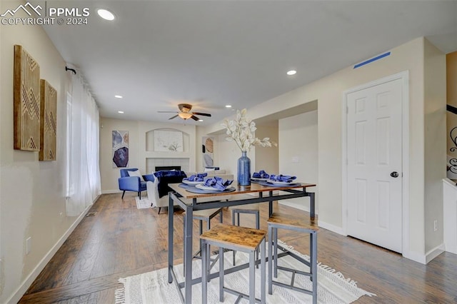 dining space featuring dark wood-type flooring, a fireplace, and ceiling fan