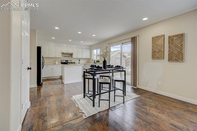 kitchen featuring a kitchen island, white cabinetry, stainless steel refrigerator, dark wood-type flooring, and sink