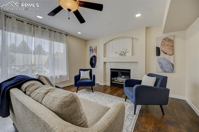 living room featuring a tiled fireplace, wood-type flooring, and ceiling fan