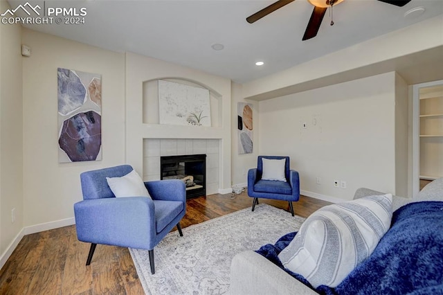 living room with dark wood-type flooring, a fireplace, and ceiling fan