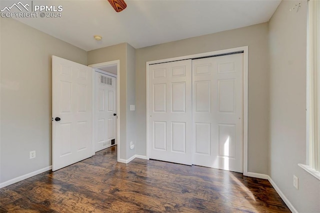 unfurnished bedroom with a closet and dark hardwood / wood-style flooring