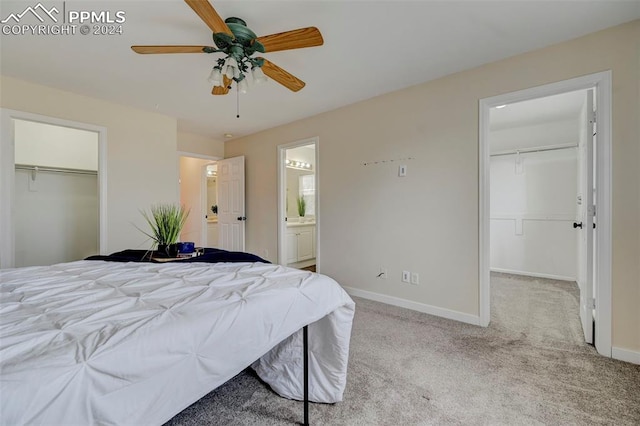 bedroom with a spacious closet, ceiling fan, ensuite bathroom, and light colored carpet