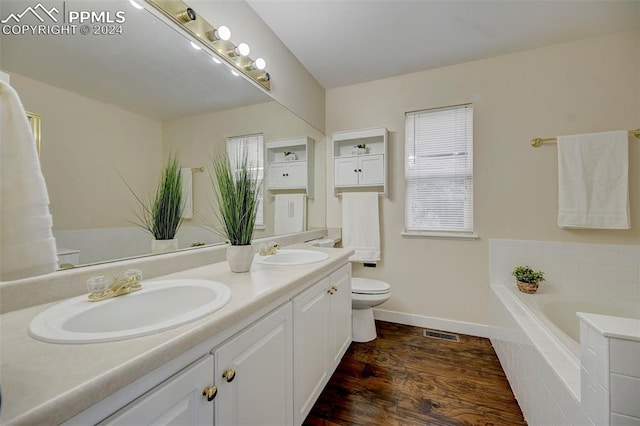 bathroom with vanity, a relaxing tiled tub, toilet, and hardwood / wood-style flooring