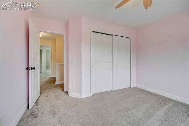 unfurnished bedroom with light colored carpet, a closet, and ceiling fan