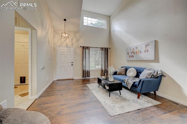 living room with a high ceiling, a chandelier, and hardwood / wood-style floors