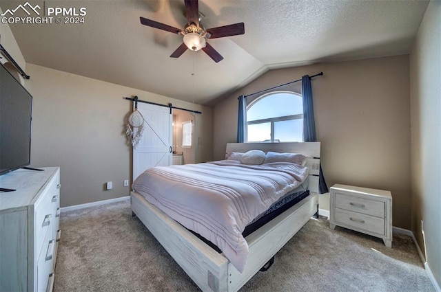 carpeted bedroom featuring lofted ceiling, ceiling fan, a barn door, and a textured ceiling