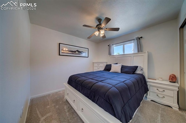 carpeted bedroom with ceiling fan and a textured ceiling