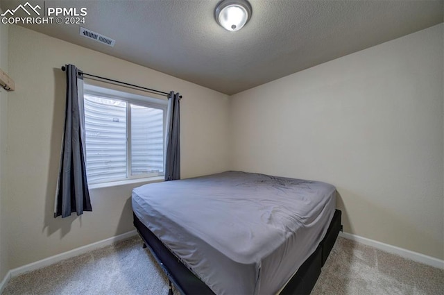 bedroom featuring light colored carpet and a textured ceiling