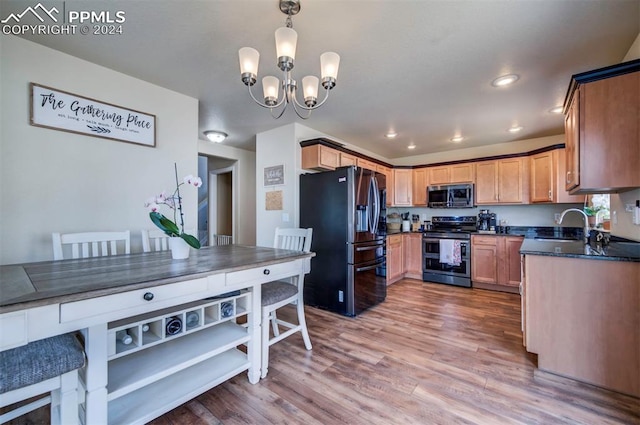 kitchen featuring appliances with stainless steel finishes, pendant lighting, sink, and light hardwood / wood-style floors