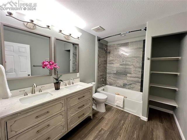 full bathroom with toilet, tiled shower / bath, hardwood / wood-style flooring, vanity, and a textured ceiling