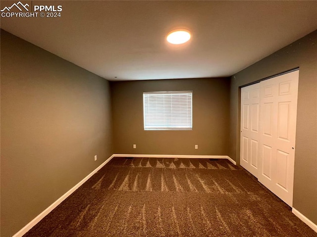 unfurnished bedroom with a closet and dark carpet