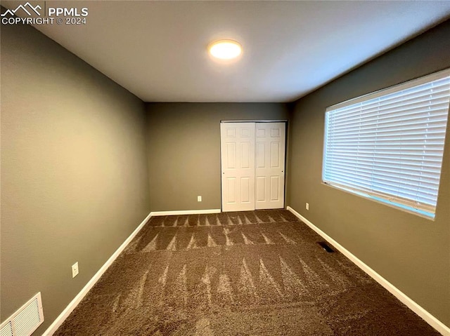 unfurnished bedroom with a closet and dark carpet