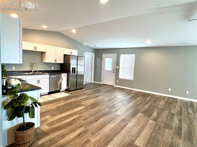 kitchen featuring white cabinets, hardwood / wood-style flooring, appliances with stainless steel finishes, and lofted ceiling