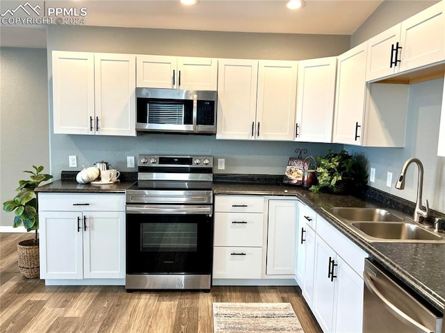 kitchen featuring appliances with stainless steel finishes, light wood-type flooring, sink, and white cabinetry