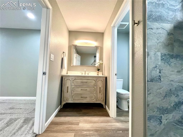 bathroom with hardwood / wood-style floors, toilet, vanity, and a textured ceiling