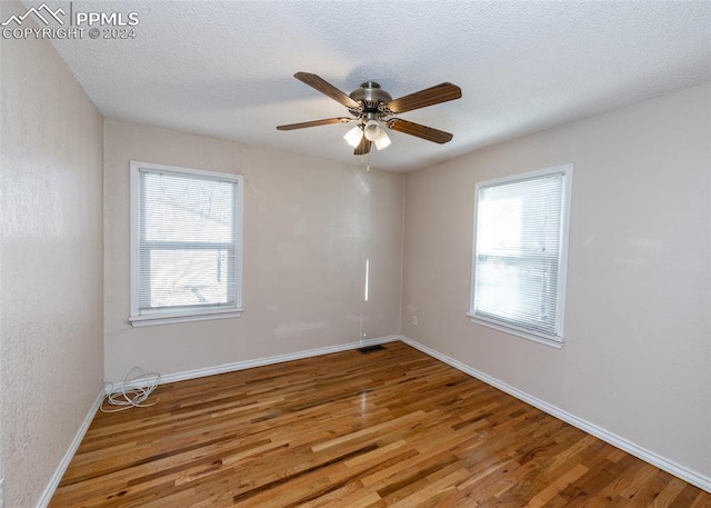 spare room featuring hardwood / wood-style flooring, ceiling fan, a healthy amount of sunlight, and a textured ceiling