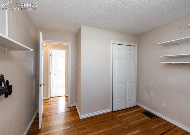 unfurnished bedroom with hardwood / wood-style flooring, a textured ceiling, and a closet