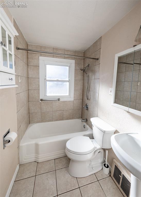 full bathroom featuring toilet, tiled shower / bath combo, tile patterned floors, and sink