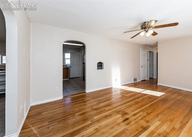 empty room with ceiling fan, hardwood / wood-style floors, and a textured ceiling