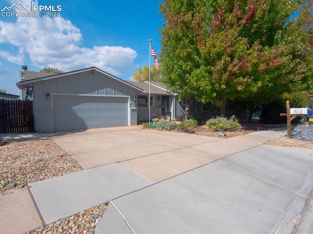 ranch-style home with an attached garage, brick siding, fence, driveway, and board and batten siding