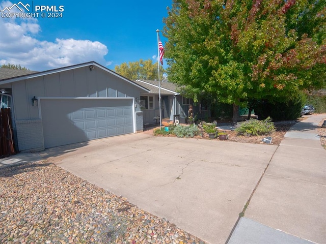 single story home with an attached garage, concrete driveway, board and batten siding, and brick siding