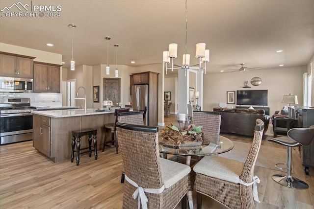 dining area with ceiling fan with notable chandelier and light hardwood / wood-style flooring