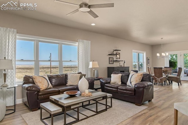 living room featuring ceiling fan with notable chandelier and light wood-type flooring