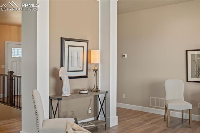 living area featuring ornate columns and hardwood / wood-style floors