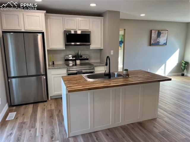 kitchen with light hardwood / wood-style floors, sink, backsplash, white cabinets, and appliances with stainless steel finishes