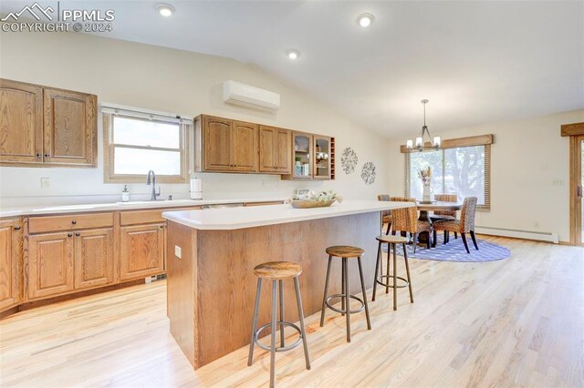 kitchen with light hardwood / wood-style floors, a wall unit AC, pendant lighting, vaulted ceiling, and a center island