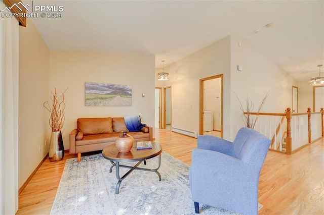 living room featuring a notable chandelier, washer / clothes dryer, light hardwood / wood-style floors, and baseboard heating