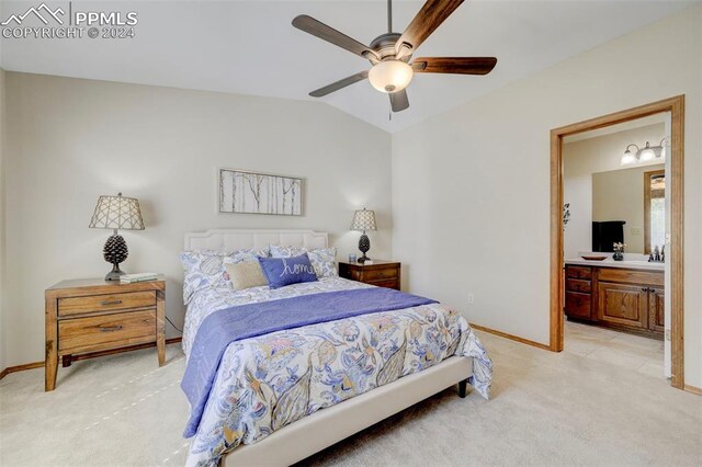 bedroom featuring ceiling fan, light colored carpet, vaulted ceiling, and ensuite bath