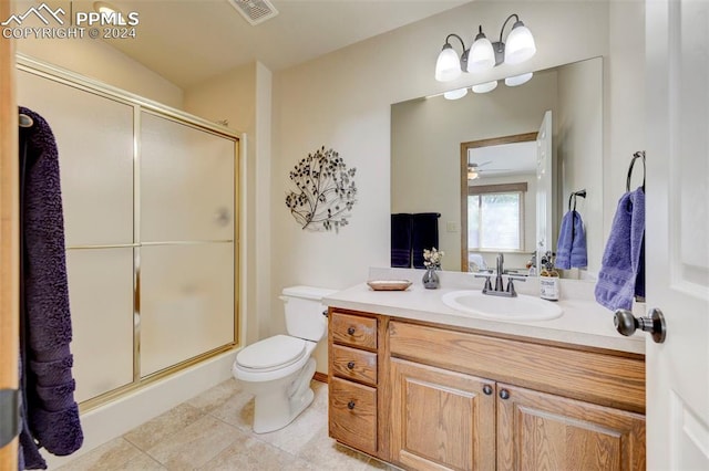 bathroom with tile patterned flooring, ceiling fan, toilet, an enclosed shower, and vanity