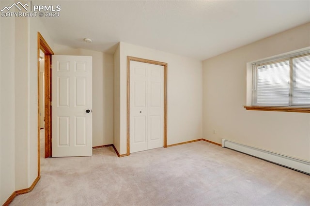 unfurnished bedroom with light colored carpet, a baseboard radiator, and a closet