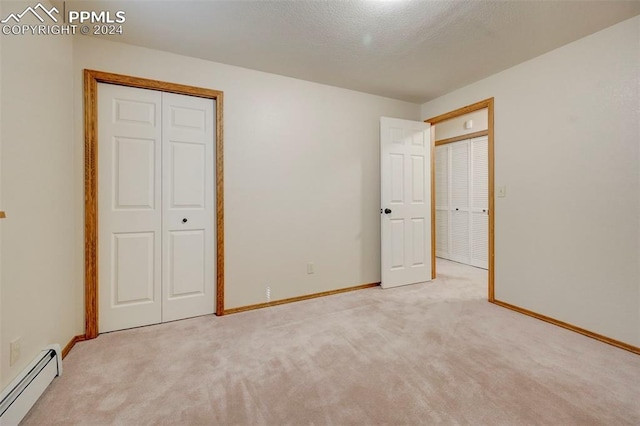 unfurnished bedroom featuring baseboard heating, a textured ceiling, and light carpet