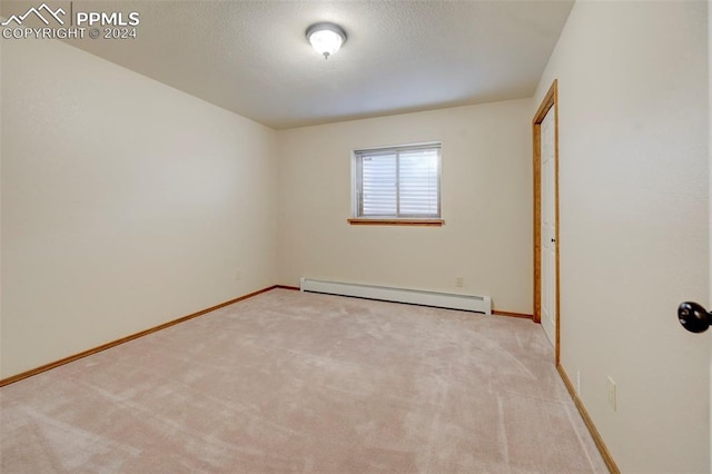 carpeted spare room with baseboard heating and a textured ceiling