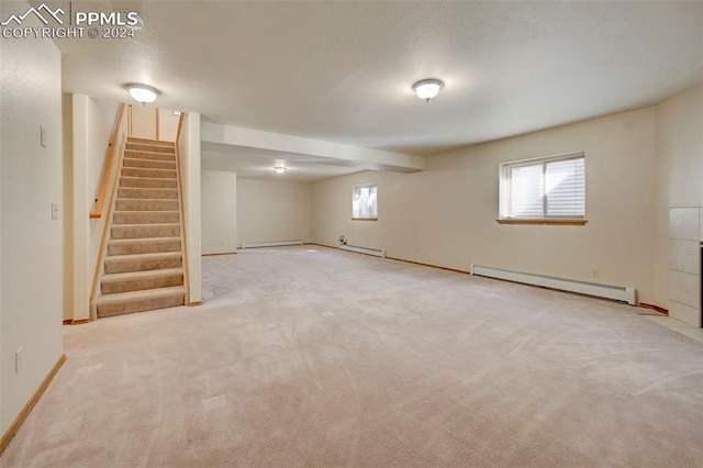 basement featuring light colored carpet, a textured ceiling, and a baseboard radiator