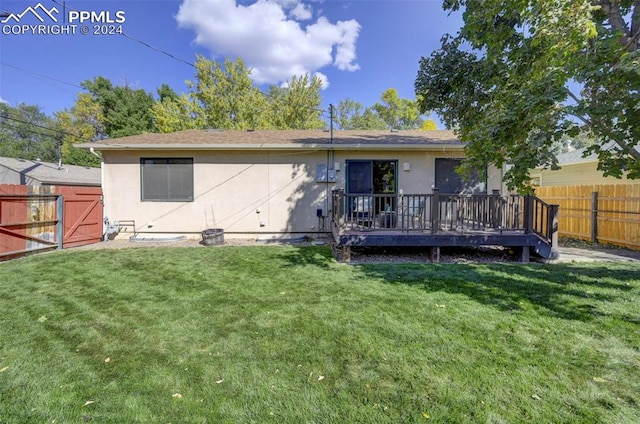 rear view of house featuring a wooden deck and a lawn